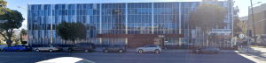 Front-facing exterior view of a multi-story medical office building with blue glass facade and parking in front.